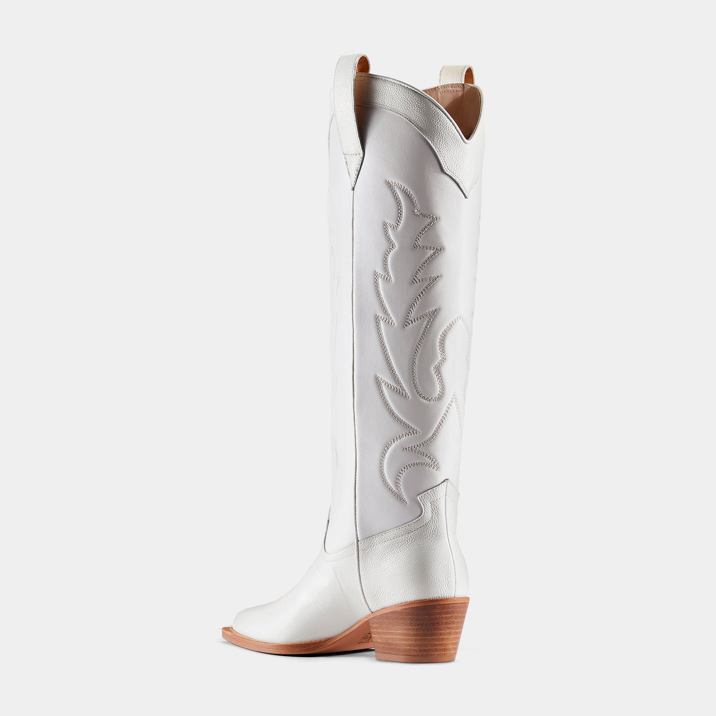A white leather cowboy boot with embroidered details and a low heel - back view.