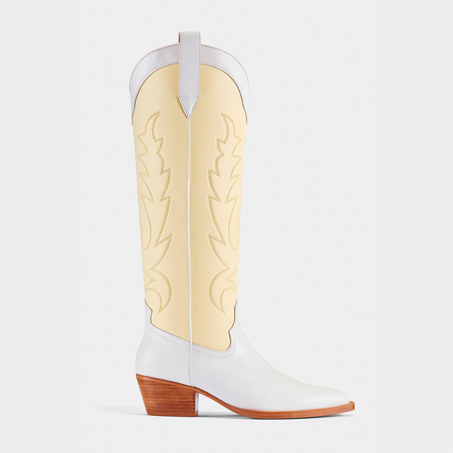 A pair of white and yellow embroidered cowboy boots with a pointed toe and low heel - side angle.