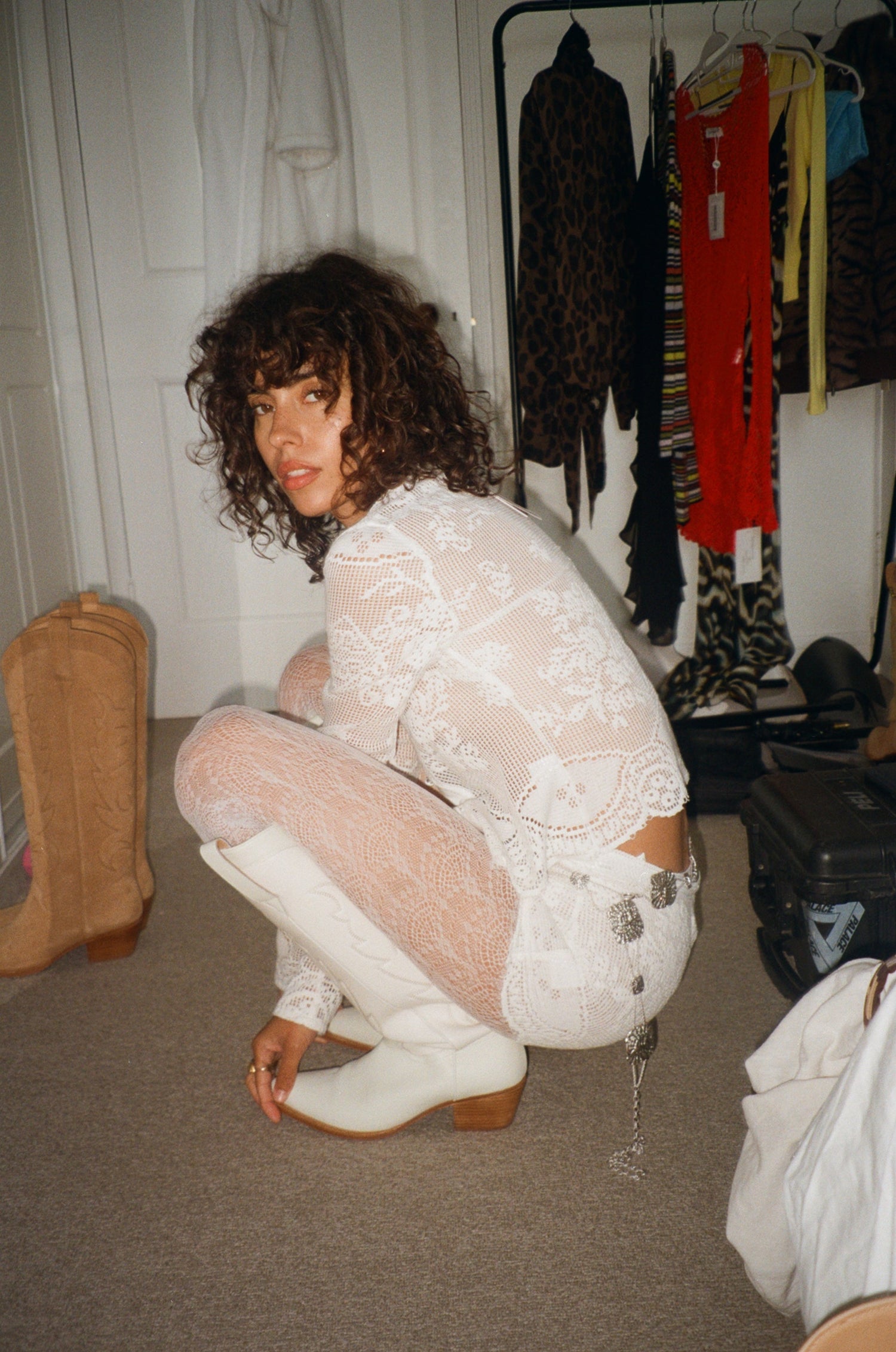 Model beside a clothes rail wearing bone white cowboy boots