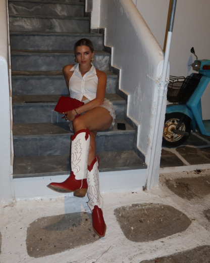 Georgie Young from Rallee Gummies in Mykonos, sitting on stone steps wearing red and white cowboy boots.