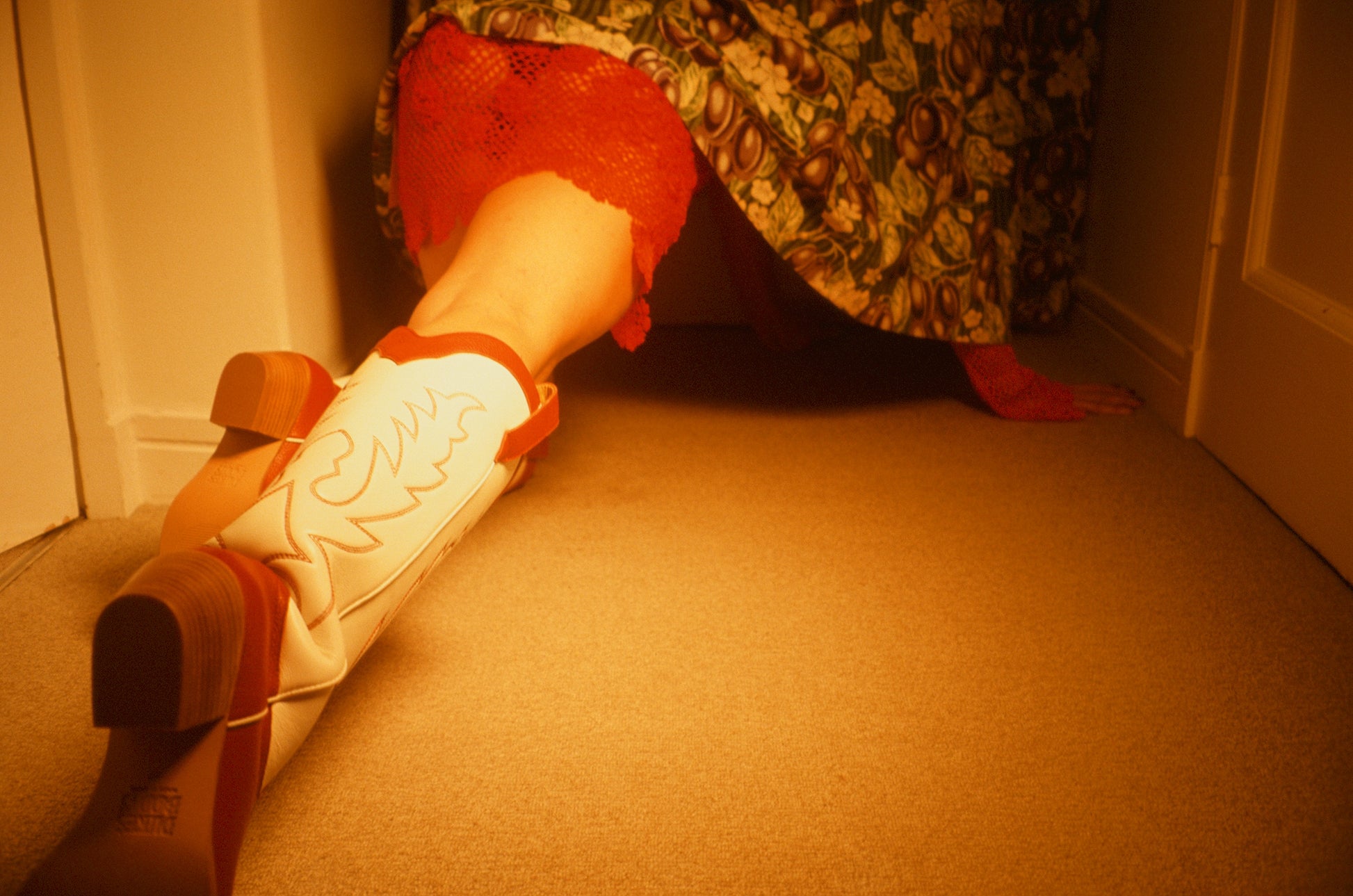 Person wearing a red and white cowboy boot behind a curtain.