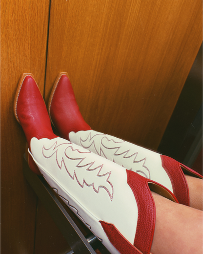 Red and white cowboy boots with red embroidery in a wooden panelled lift.