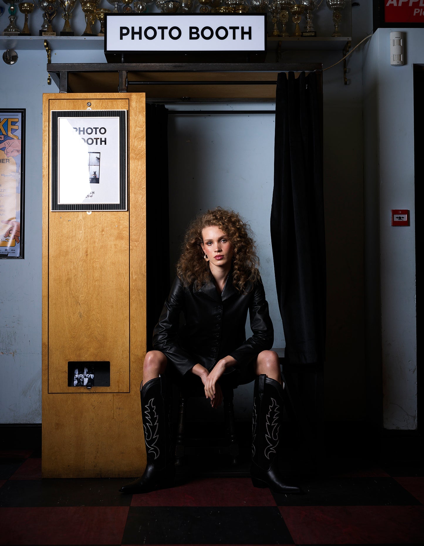 Model in photobooth wearing black cowboy boots