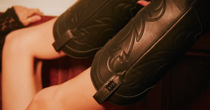 Close up view of black cowboy boots with metal branded logo