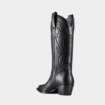 Black cowboy boot with embroidered design and metal branding on a light grey background - back view.