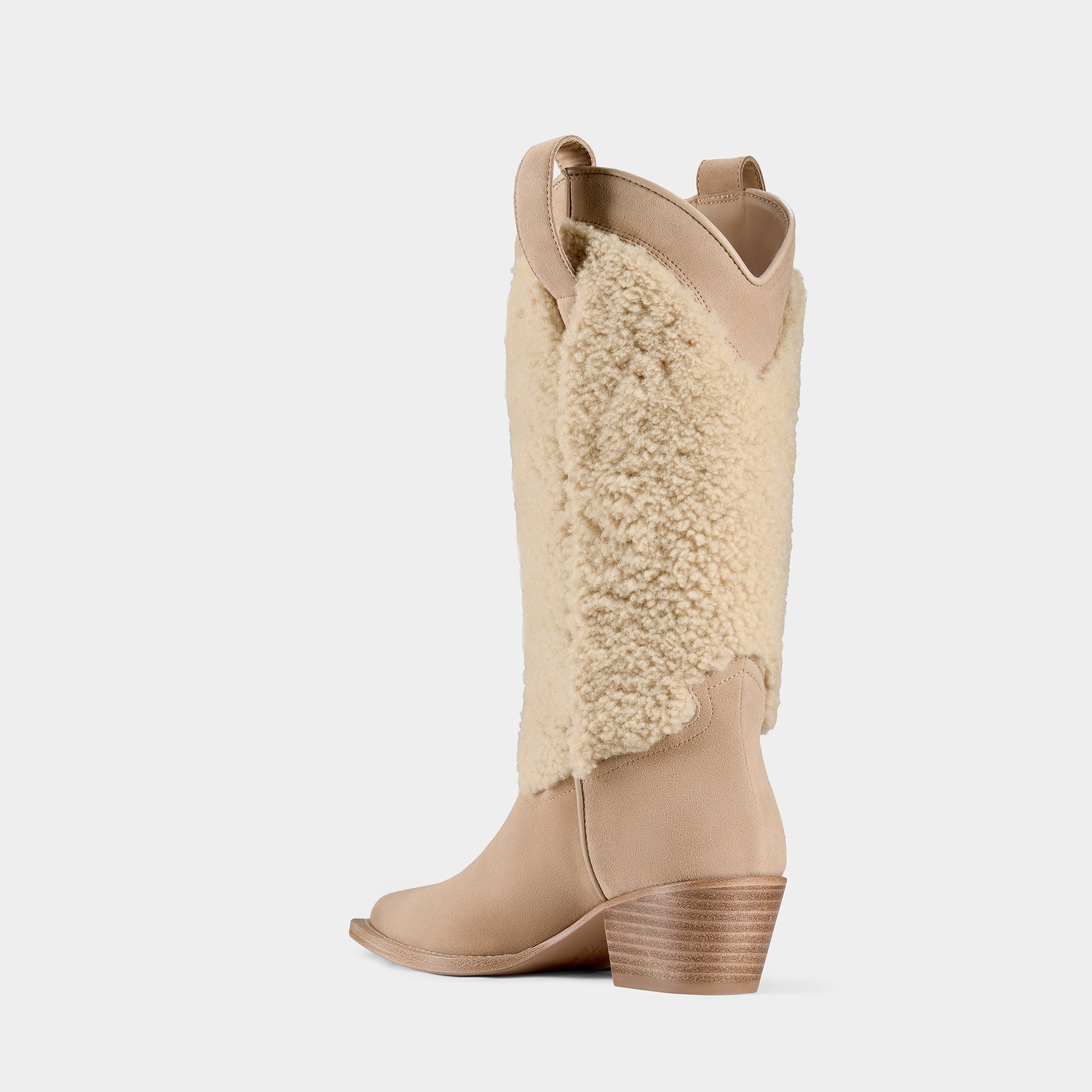 Tan suede cowboy boot with shearling shaft on a light grey background - side angle.