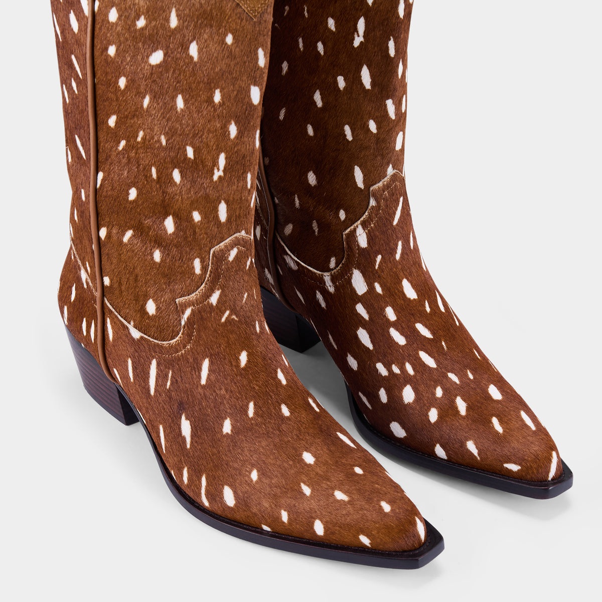 Fawn print calf hair cowboy boots on a light grey background - close up