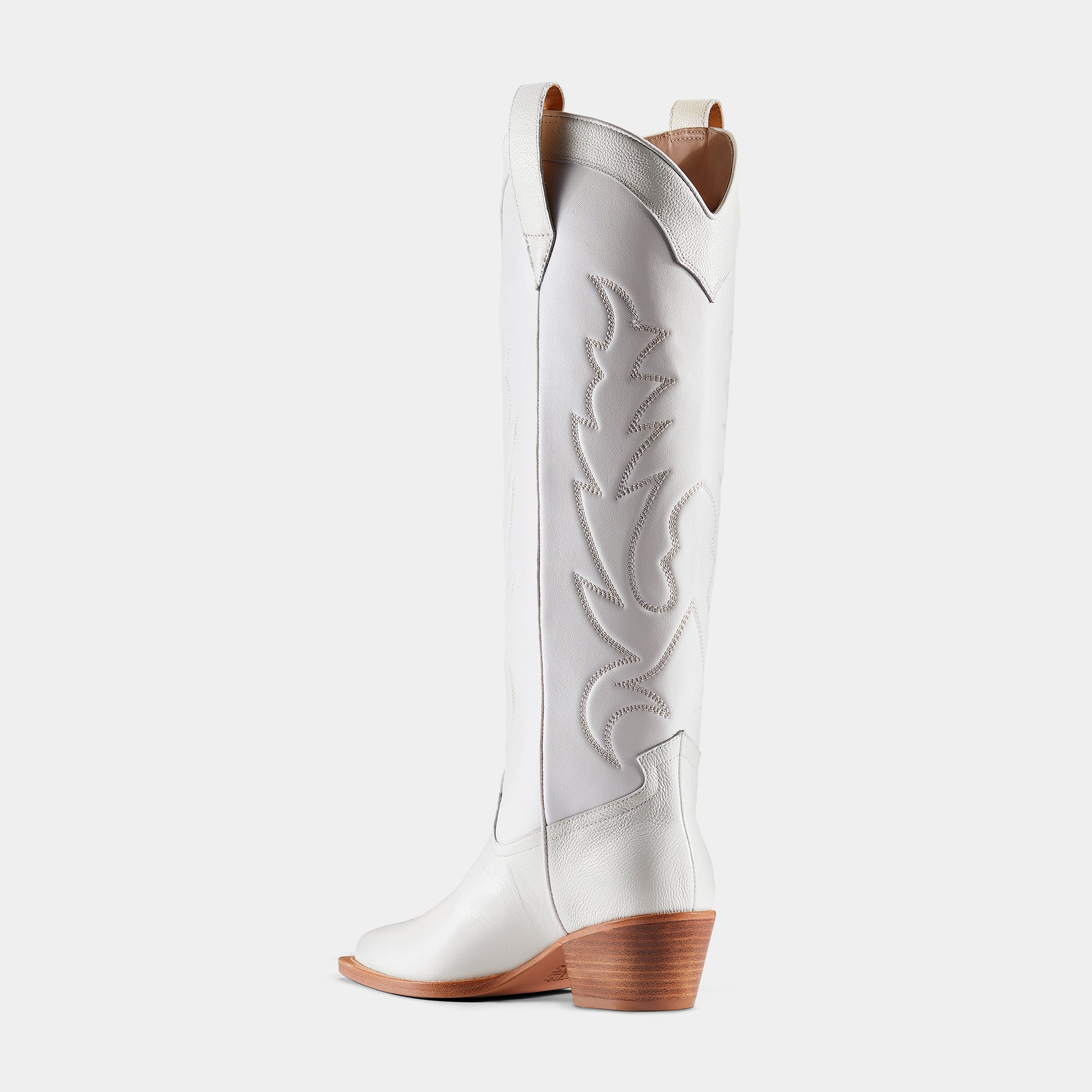 A white leather cowboy boot with embroidered details and a low heel - back view.